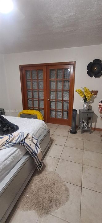 Double wooden French doors featuring multiple glass panes, complemented by ceramic tile flooring