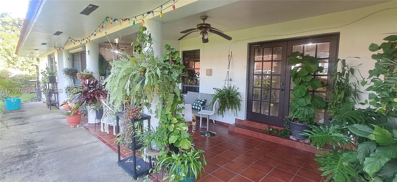 Covered patio featuring ceramic tile flooring, dual French doors with glass panes, and a ceiling-mounted fan