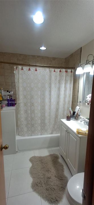 Bathroom featuring white cabinetry, tile wall surround, recessed lighting, and a three-bulb vanity fixture