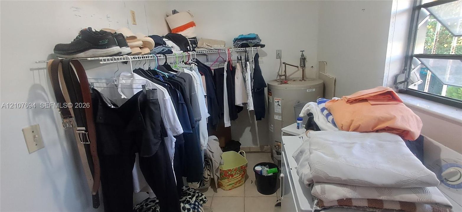 Utility area featuring white wire shelving, a cylindrical water heater, and natural light from a single window