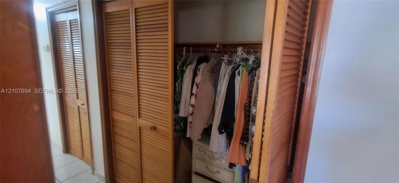 Storage area featuring wood louvered bifold doors and built-in wooden closet rod