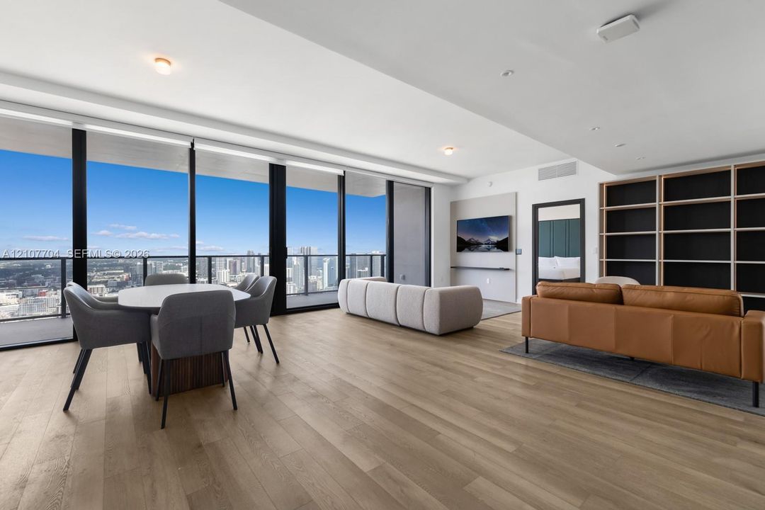 Floor-to-ceiling windows, wood-finish flooring, built-in shelving, recessed lighting, and a private balcony
