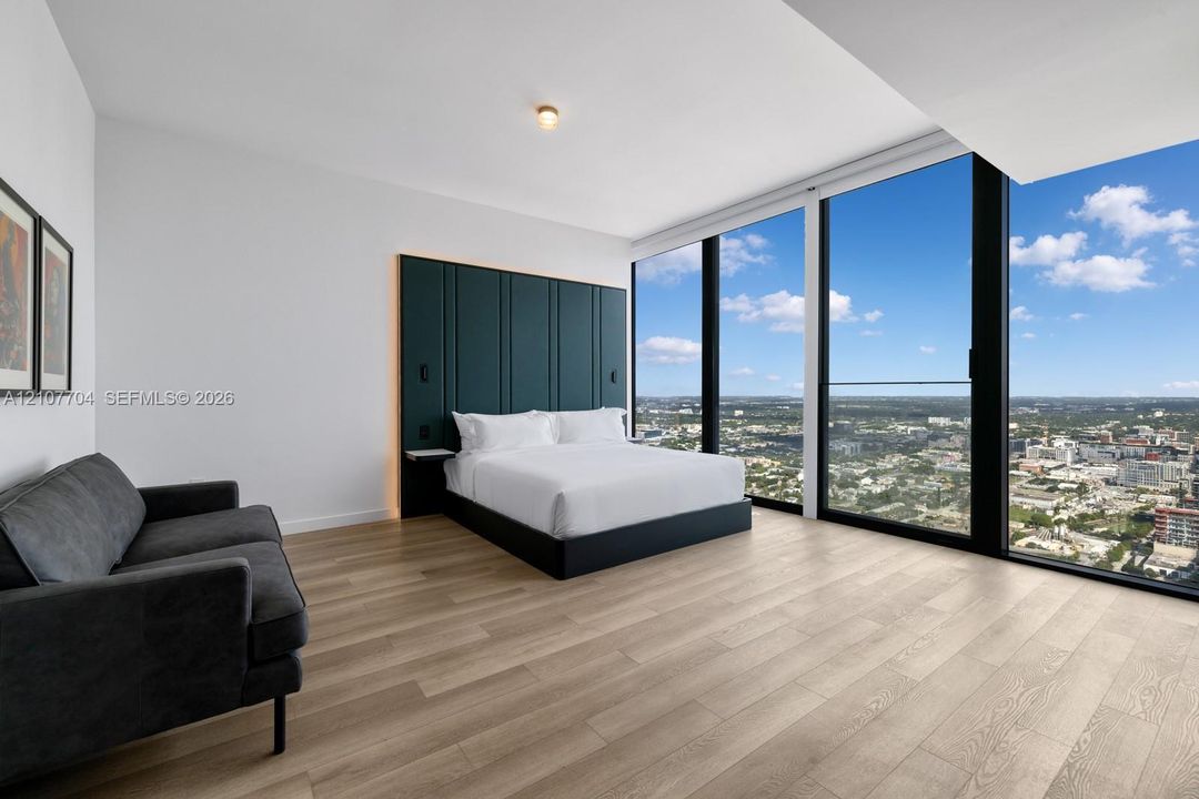 Floor-to-ceiling windows, wood-finish flooring, and built-in upholstered headboard wall paneling