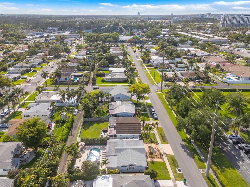 Aerial perspective featuring established residential streets, manicured landscaping, mature trees, and private in-ground swimming pools