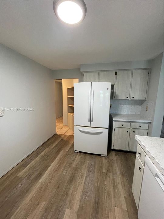 Kitchen featuring light-toned cabinetry, wood-finish flooring, stone-patterned countertops, and a full-size french-door refrigerator