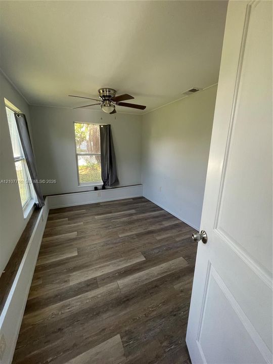 Interior space featuring wood-finish flooring, two windows, and a ceiling fan with integrated light fixture