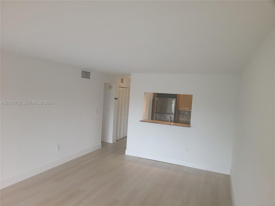Interior featuring light-toned wood-finish flooring, a pass-through opening to the kitchen, and bifold closet doors