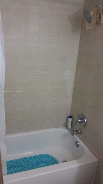 Bathtub featuring large-format ceramic wall tile surround and chrome finish plumbing fixtures