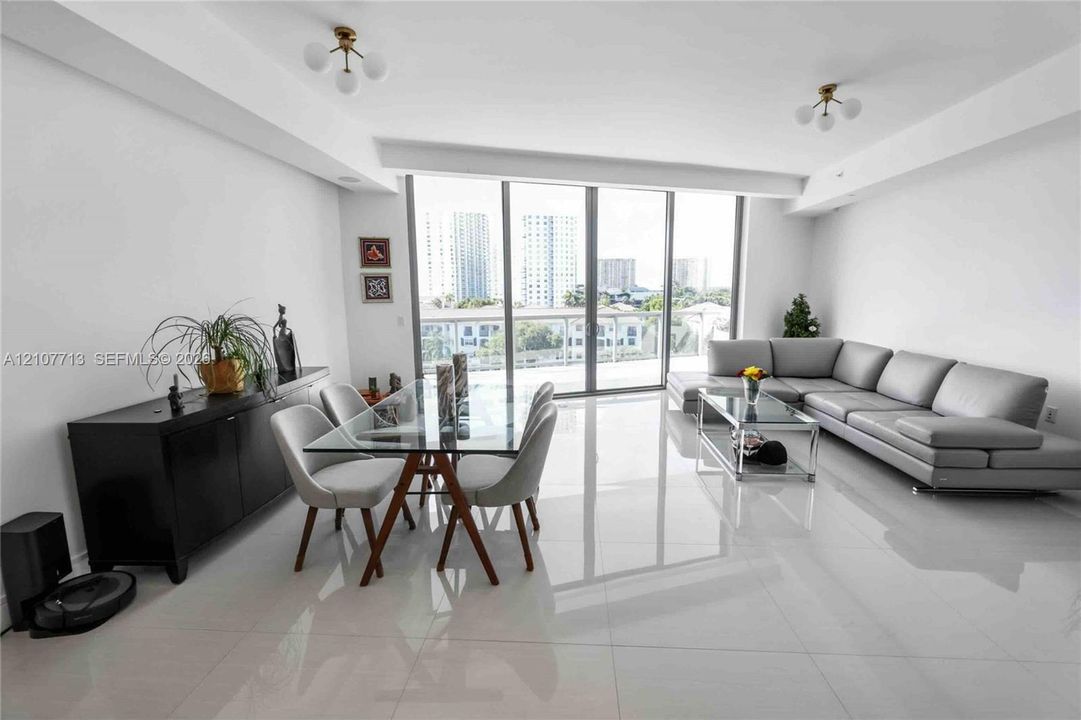 Floor-to-ceiling glass panel doors, polished tile flooring, recessed ceiling lighting, and multi-globe chandelier fixtures