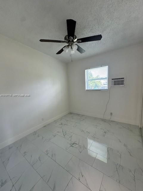 Room featuring large-format veined tile flooring, a multi-blade ceiling fan with integrated lighting, and a wall-mounted air conditioning unit