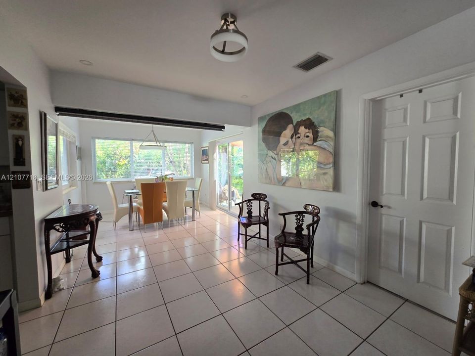 Interior space featuring tile flooring, neutral wall tones, six-panel interior door, multi-pane window, and decorative ceiling light fixture