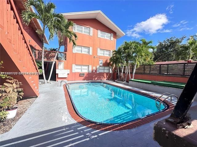 Multi-story exterior featuring a swimming pool, concrete pool deck, brick-edge coping, built-in bench seating, and palm trees