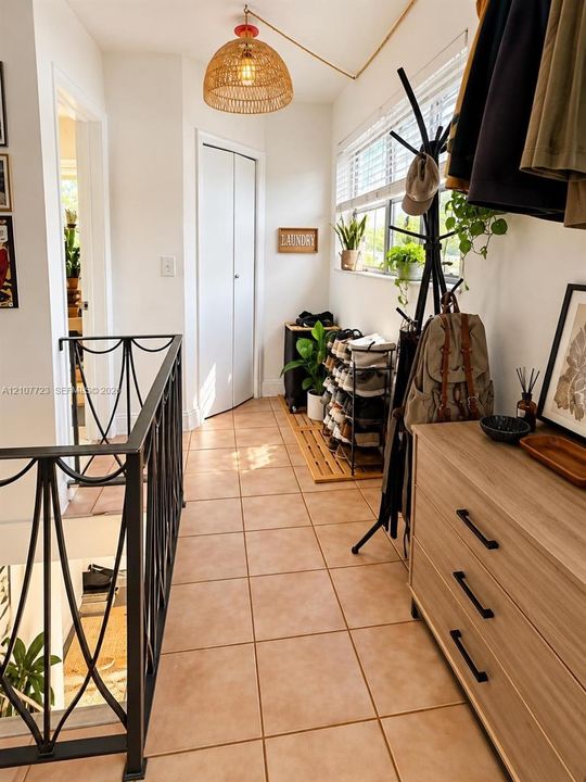 Ceramic tile flooring, wrought iron staircase railing, textured dome pendant lighting, and multi-panel window with horizontal blinds
