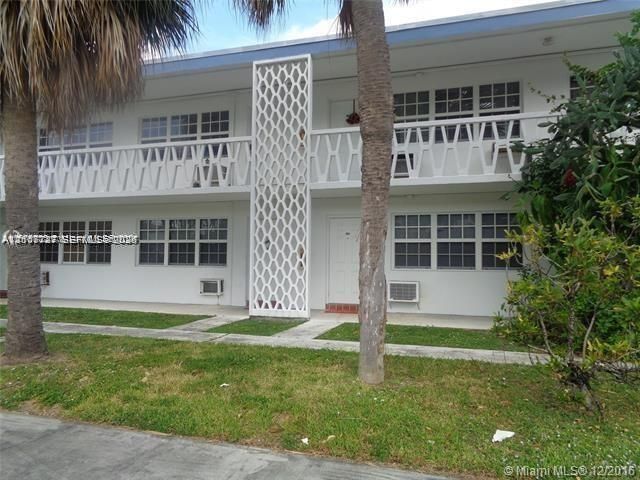 Two-story exterior featuring white stucco siding, decorative geometric screen-block masonry, and a concrete balcony with custom railings