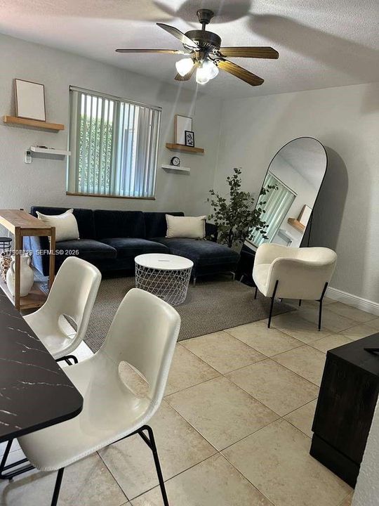 Neutral tile flooring, multi-light ceiling fan with integrated fixture, and wall-mounted floating wood shelves