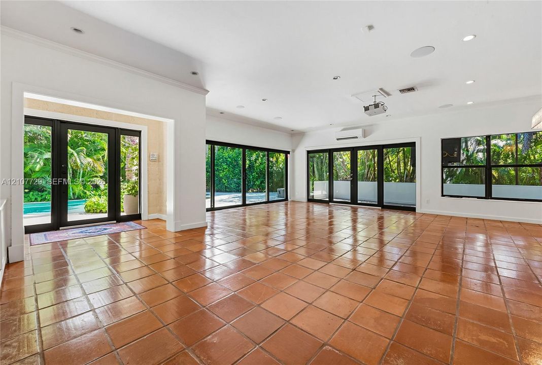 Open-concept interior featuring large-format ceramic tile flooring, multi-panel sliding glass doors, recessed lighting, and a wall-mounted climate control unit