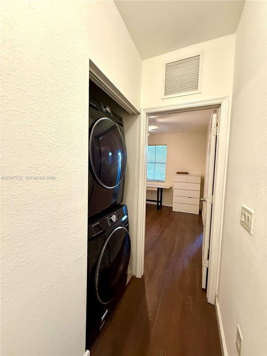 Stackable laundry unit with high-gloss finish, wood-finish flooring, and crisp white wall paint