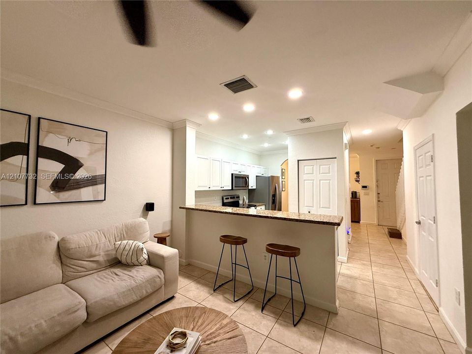 Kitchen featuring white cabinetry, a stone-surfaced breakfast bar, and recessed lighting