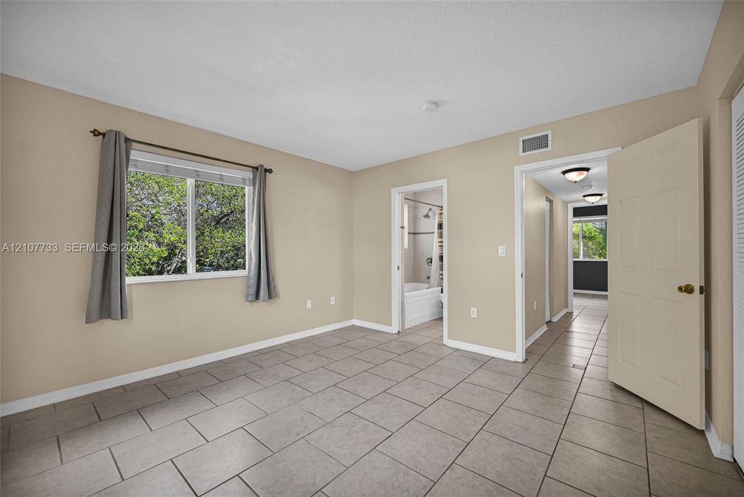 Neutral-toned room featuring rectangular tile flooring, a horizontal sliding window, and interior paneled doors