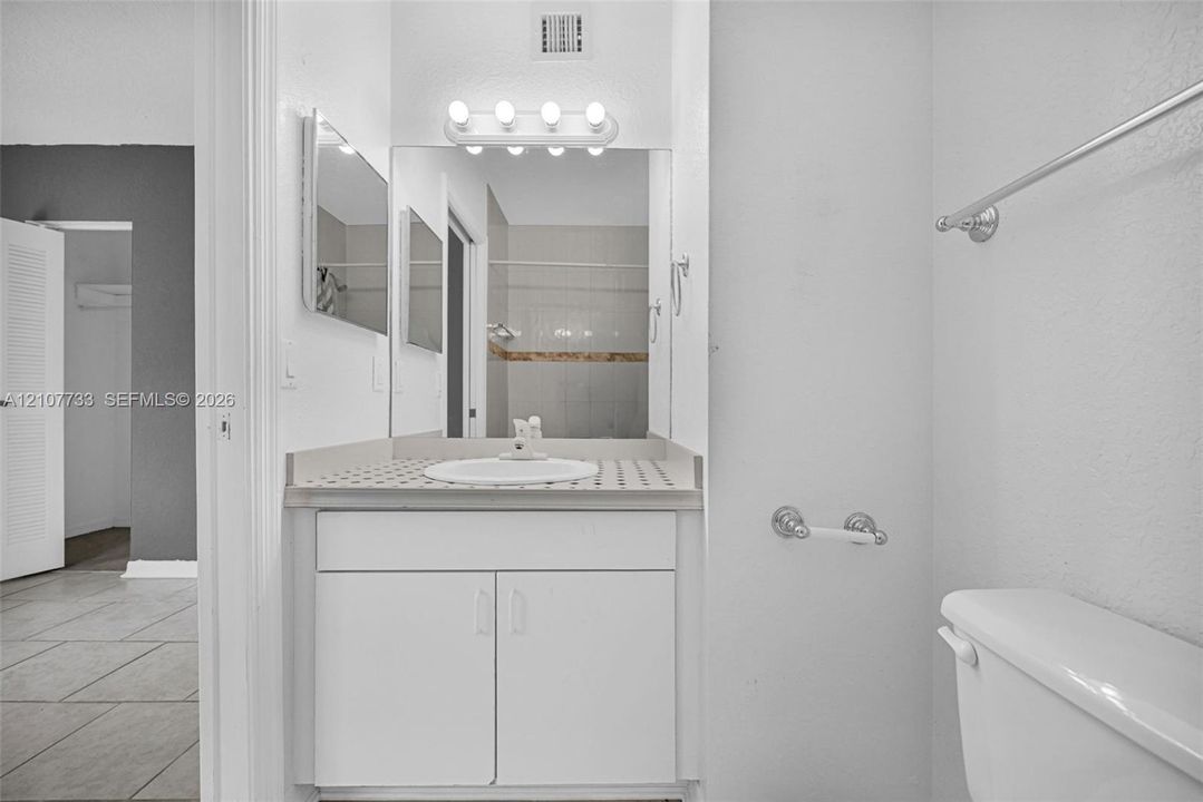 Bathroom featuring a vanity with a circular drop-in sink, tiled countertop, five-light wall-mounted vanity fixture, and large square mirror