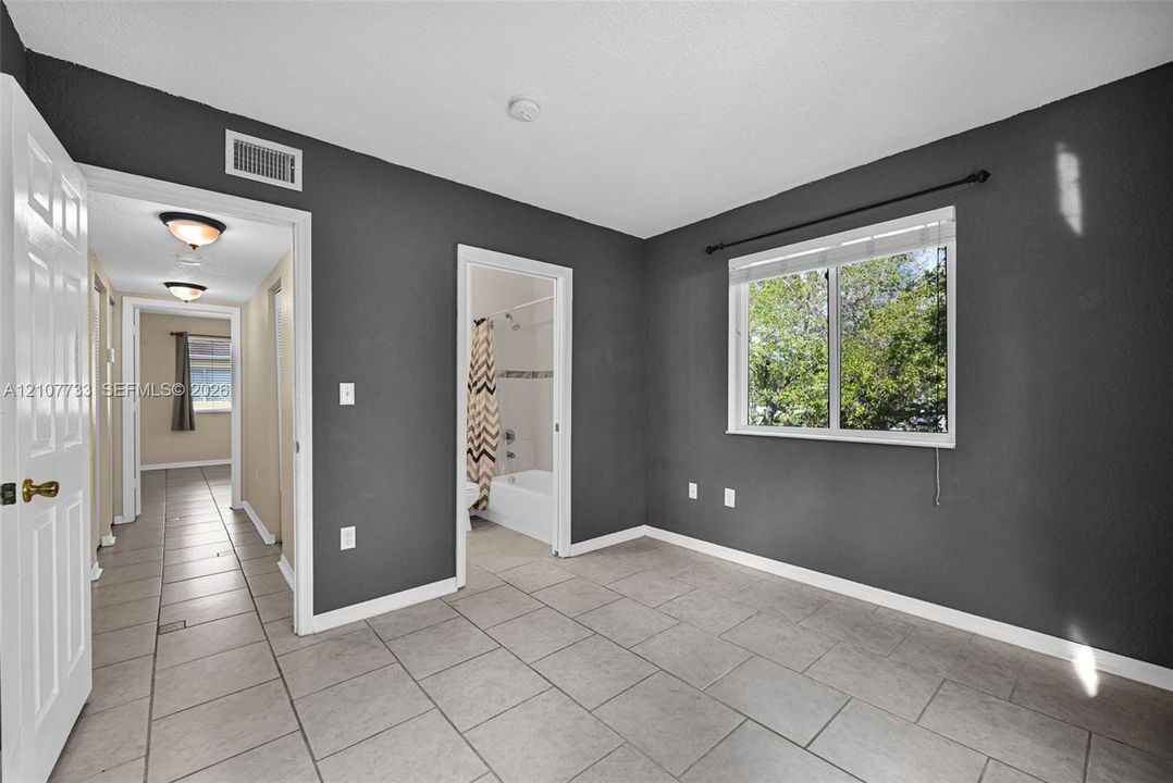 Room featuring large-format ceramic tile flooring, a single-pane window with white trim, and neutral wall tones