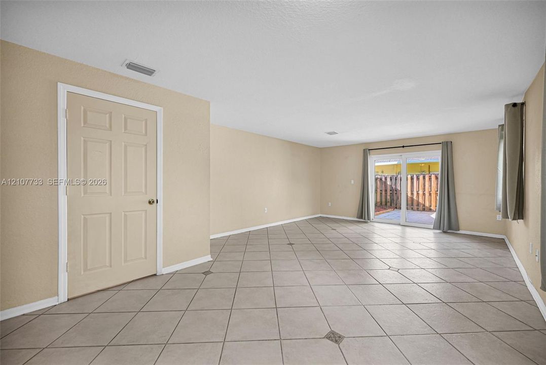 Interior space featuring large-format ceramic tile flooring with decorative stone accents, neutral-toned walls, and sliding glass doors with direct exterior access
