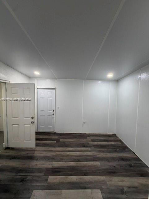 Interior room featuring wood-finish flooring, recessed lighting, and white paneled walls, with two six-panel entry doors