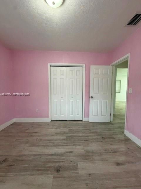 Room featuring wood-finish flooring, dual-panel closet doors, and a paneled entry door