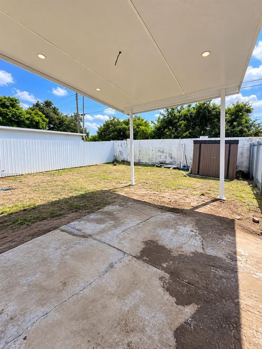 Covered patio featuring a concrete slab and recessed lighting, set within a fenced backyard