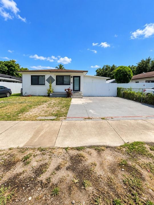 Single-story exterior featuring white stucco siding, a concrete driveway, and a white privacy fence