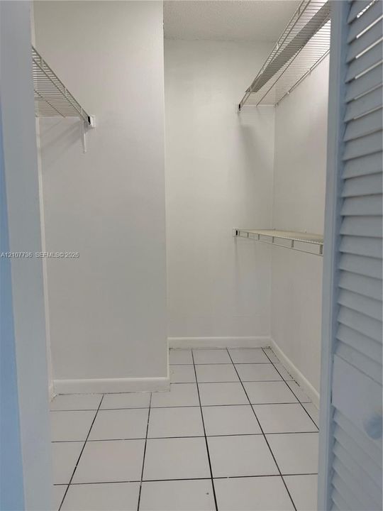 Walk-in closet featuring white ceramic tile flooring and multi-level wire shelving