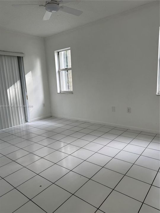 Interior space featuring white tile flooring, vertical window blinds, and a ceiling fan