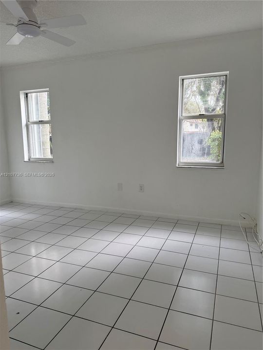 Bright interior featuring white tile flooring, dual windows, and an overhead ceiling fan
