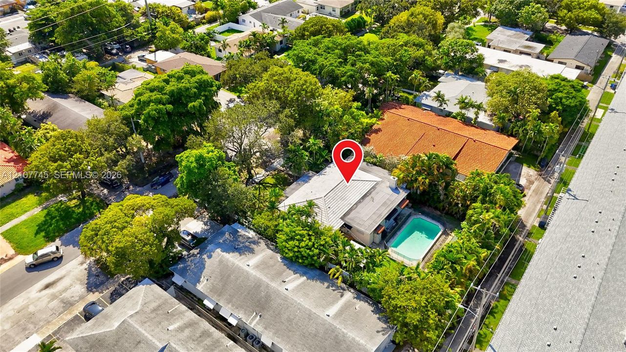 Aerial perspective featuring a tile roof, an in-ground swimming pool, and mature trees within the lot boundaries