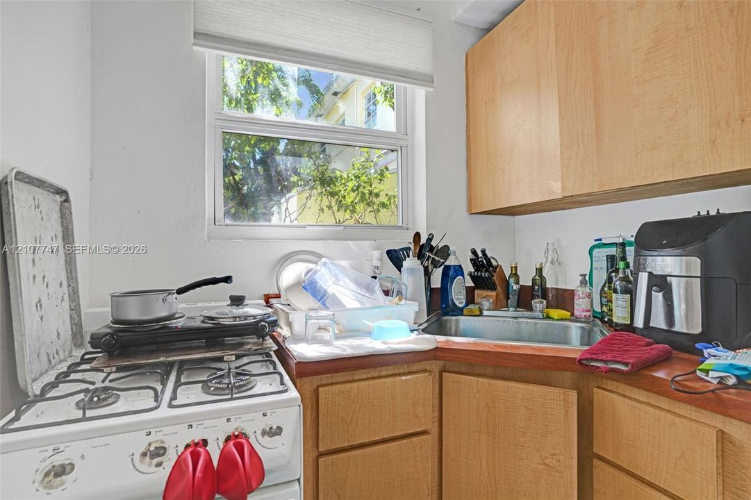 Kitchen featuring wood-finish cabinetry, stainless steel sink, solid-surface countertop, and window with built-in shade