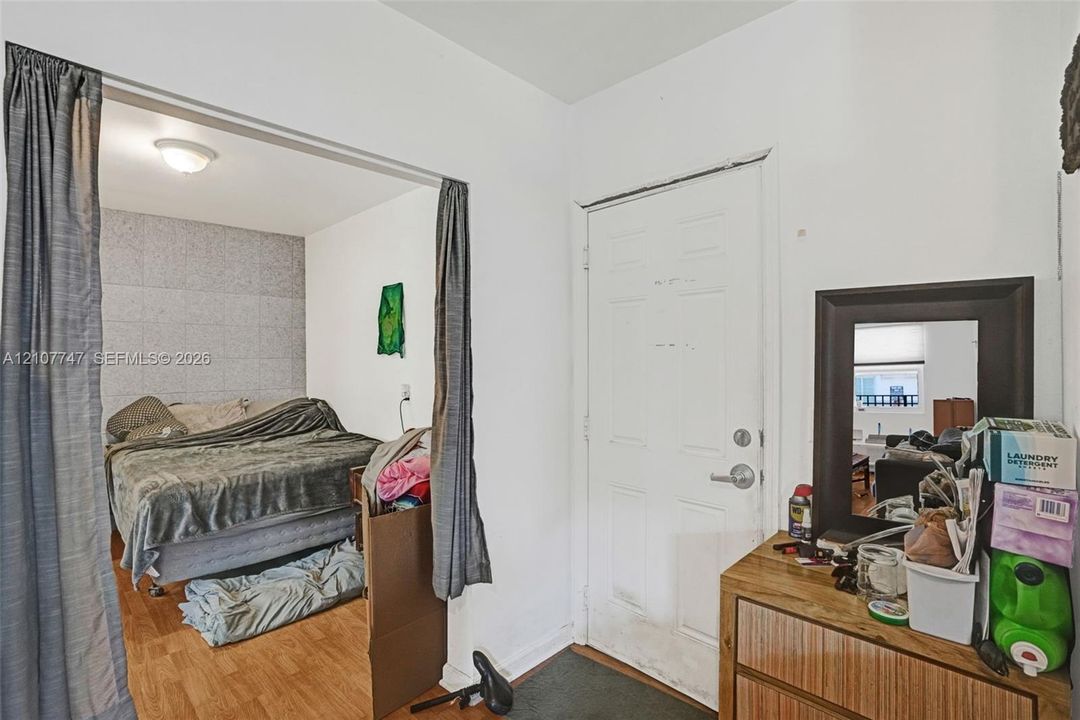 Entryway featuring a white paneled door with a metallic handle, wood-finish flooring, and a ceiling-mounted flush light fixture