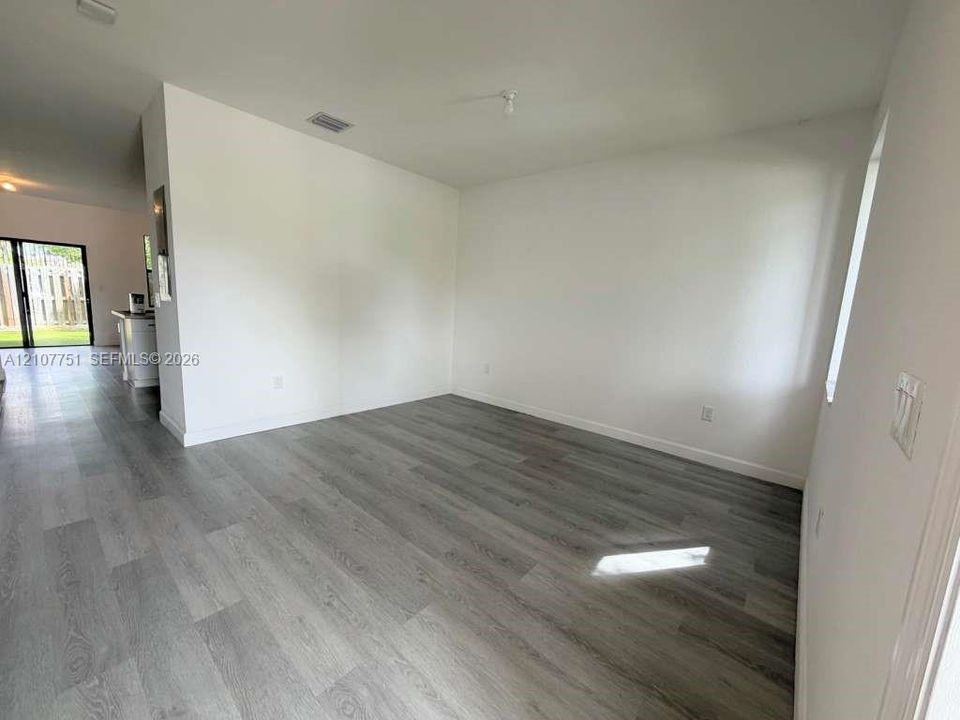 Neutral-toned wood-finish flooring, white walls, and large window