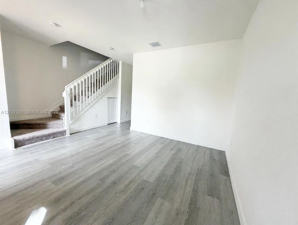 Wood-finish flooring, staircase with white railing, and built-in under-stair storage