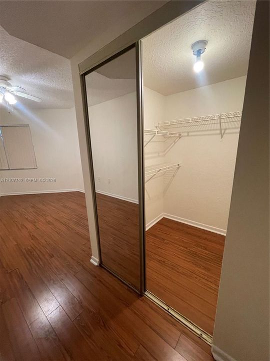 Wood-finish flooring, mirrored sliding closet doors, and wire-rack shelving