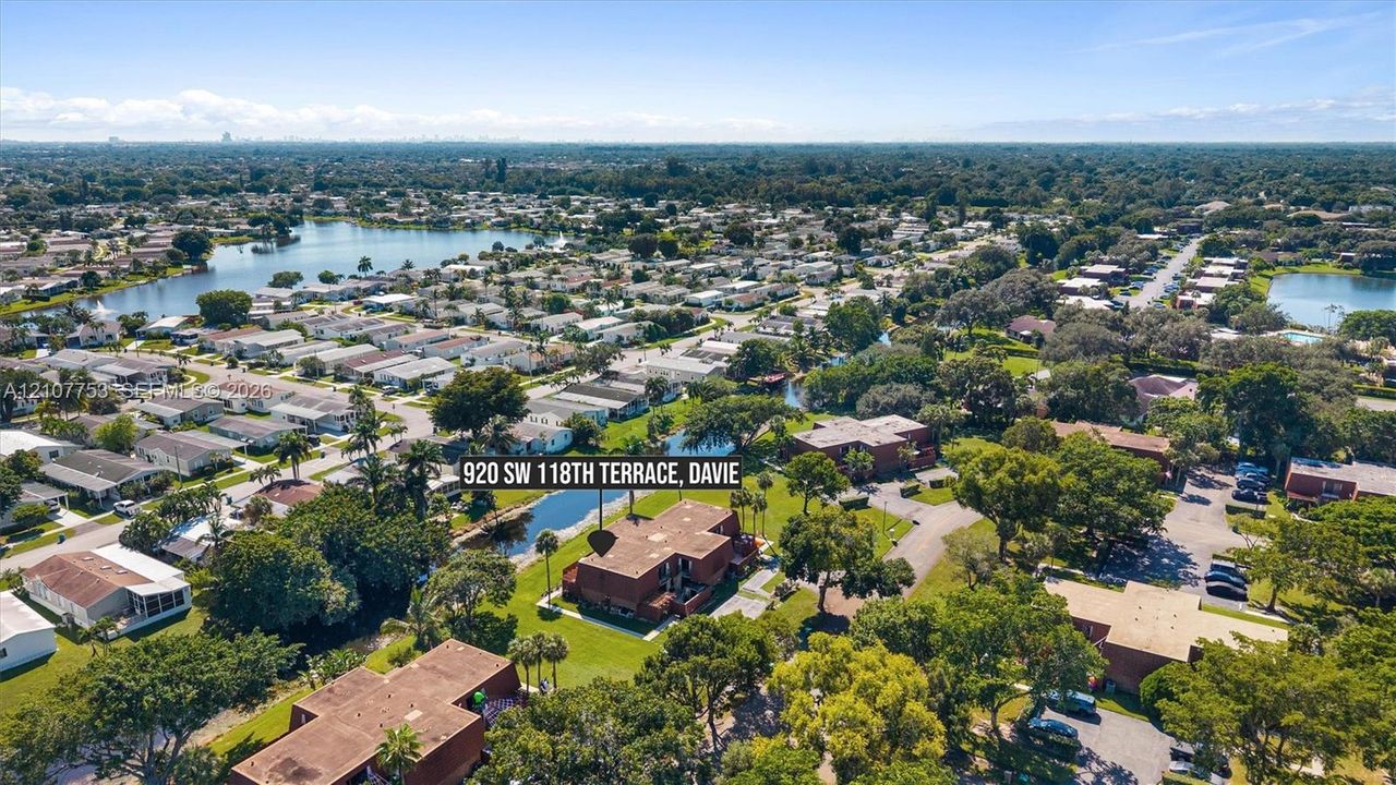 Aerial perspective featuring a multi-story building situated on a lot with direct canal frontage, expansive green space, and mature trees