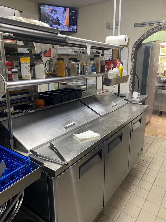 Stainless steel refrigerated prep station featuring dual top-loading compartments and integrated tiered shelving
