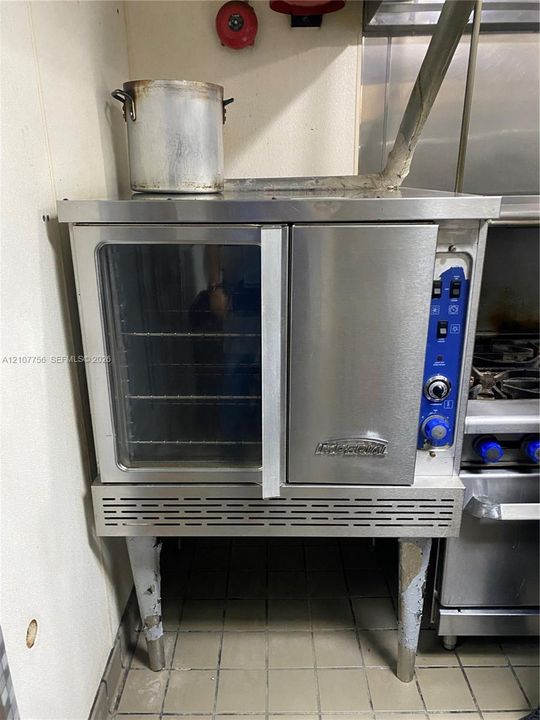 Stainless steel commercial convection oven featuring a glass-front door, integrated manual control panel, and adjustable metal legs
