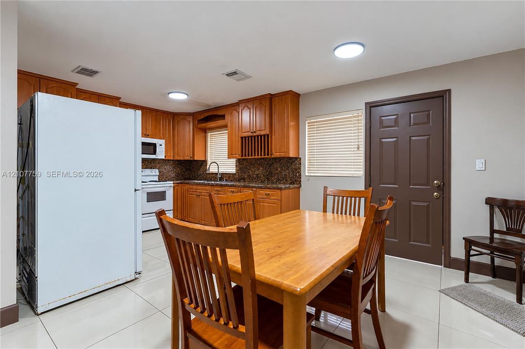 Kitchen featuring wood cabinetry, stone countertops, tiled flooring, and built-in appliances