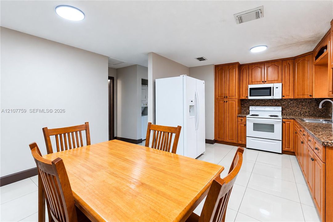 Kitchen featuring light wood cabinetry, stone-finish countertops, tile flooring, and built-in appliances