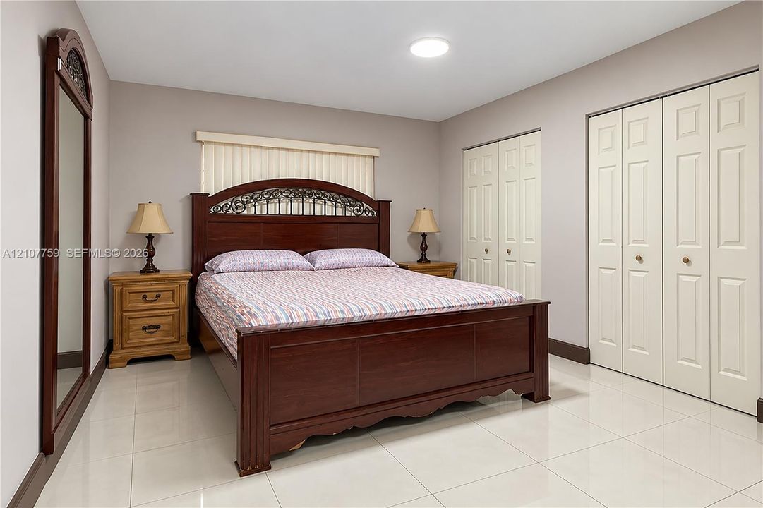 Neutral interior with light-colored tile flooring, flush-mount ceiling lighting, and dual sets of bi-fold closet doors