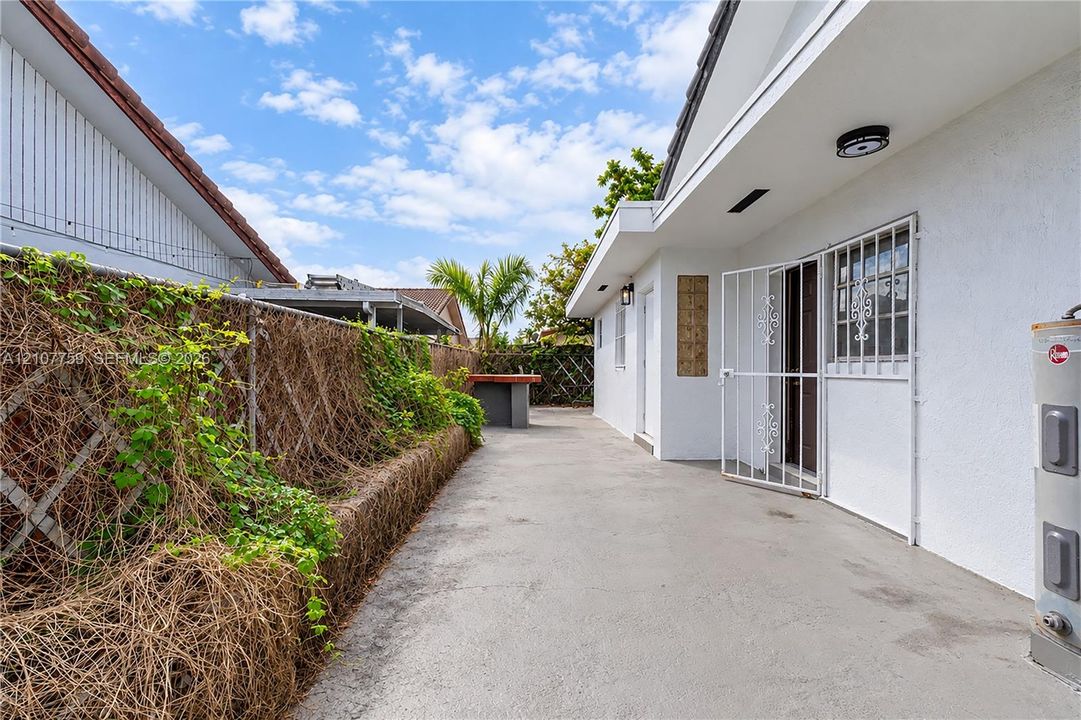 Concrete side patio with stucco exterior walls, metal security door, and built-in masonry counter