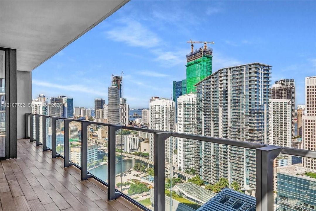 Covered balcony featuring wood-finish flooring and glass panel railing