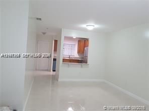 Interior space featuring light-colored tile flooring, smooth white walls, and a recessed pass-through window with a ledge