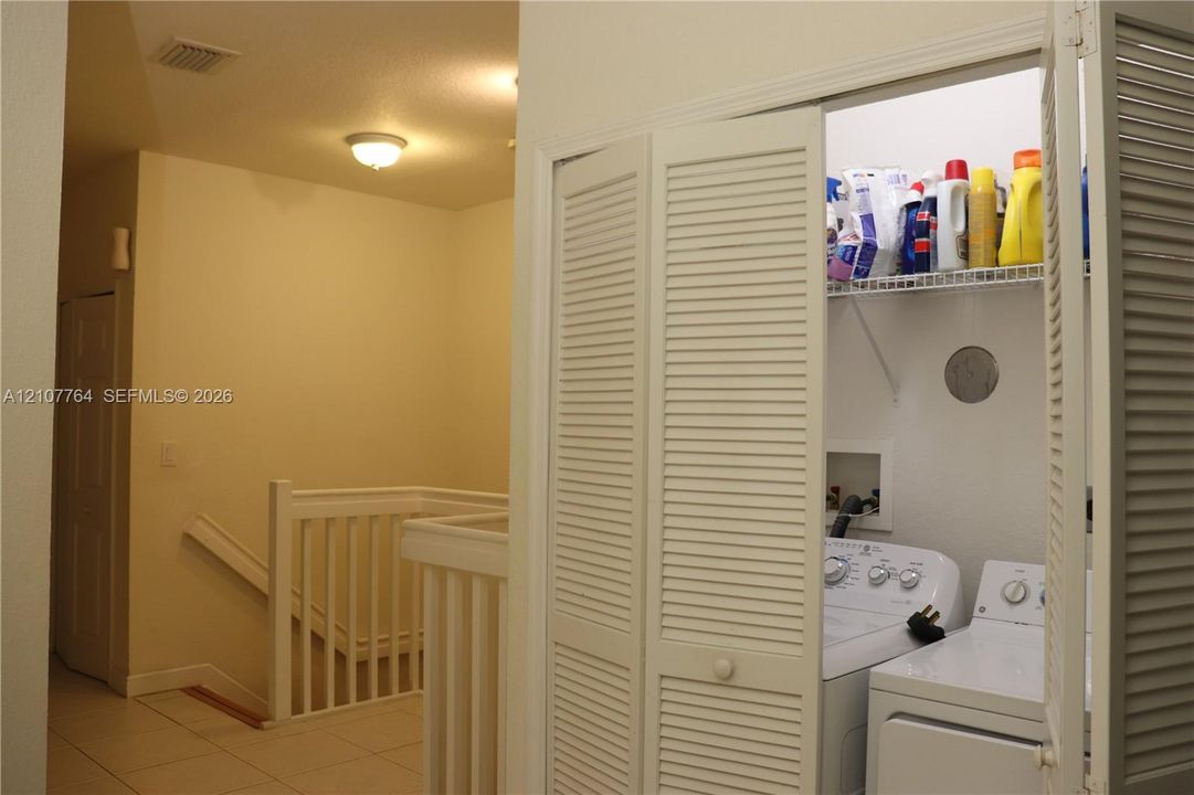 Laundry closet featuring louvered bifold doors, built-in wire shelving, and dedicated hookups for a washer and dryer