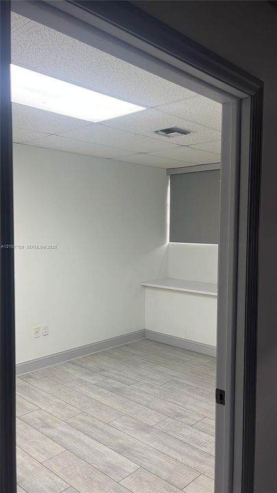 Interior space featuring wood-finish tile flooring, recessed drop-ceiling lighting, a built-in window ledge, and a neutral color palette